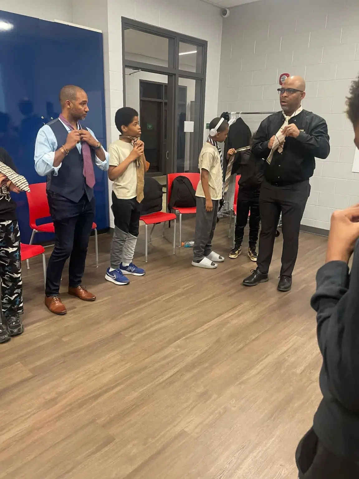 Mentors teaching young participants how to tie a necktie